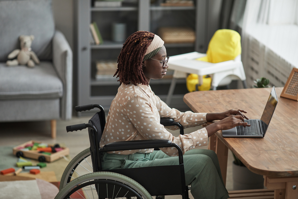 Accountant working on a laptop from her home living room scattered with toys using QuickBooks remote access to get taxes done